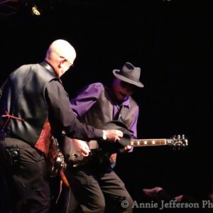 Two musicians on stage playing electric guitars
