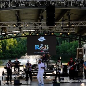 Band performing on outdoor stage, daytime concert.