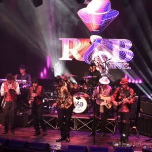 Band performing on stage with colorful lights.